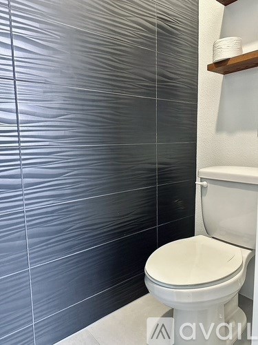 A white toilet in a bathroom with grey tiles.
