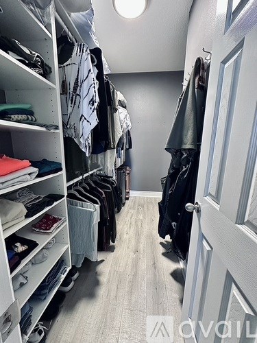 A walk-in closet with clothes hanging and shelves filled with folded clothes.