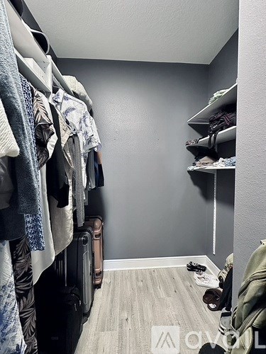 A walk in closet with clothes hanging and shelves.