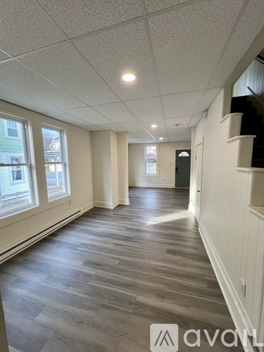 A long hallway with wood floors and white walls.