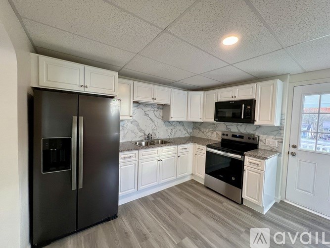 A kitchen with a black refrigerator and white cabinets.