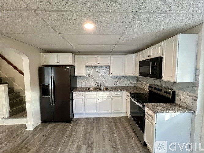 A kitchen with a black refrigerator and white cabinets.