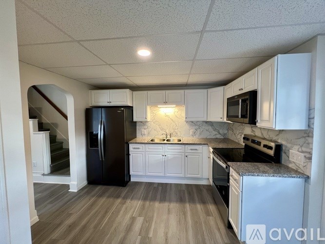 A kitchen with black and white appliances and wooden floors.