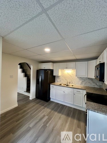 A kitchen with a refrigerator, sink, and cabinets.