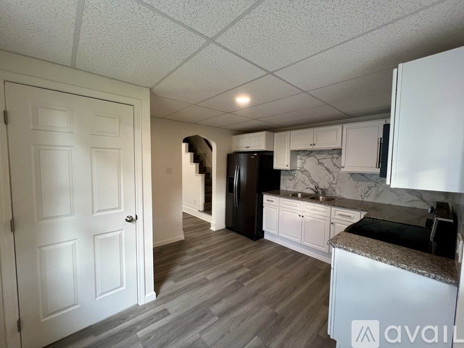 A kitchen with a black refrigerator and white cabinets.