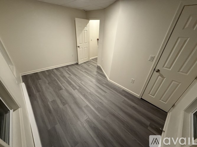 A hallway with a wooden floor and white walls.