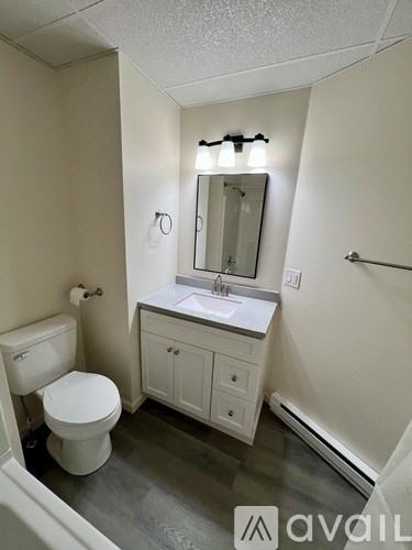 A bathroom with a toilet, sink, and mirror.