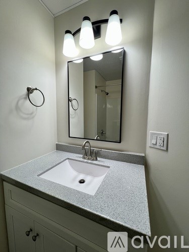A bathroom with a sink, mirror, and lights.