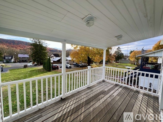 A wooden deck with a white railing and a view of a residential area.
