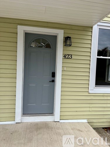 A house numbered 423 with a grey door and a window.