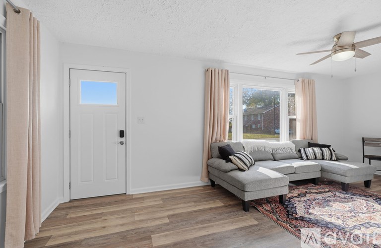 A living room with a grey couch and a rug.