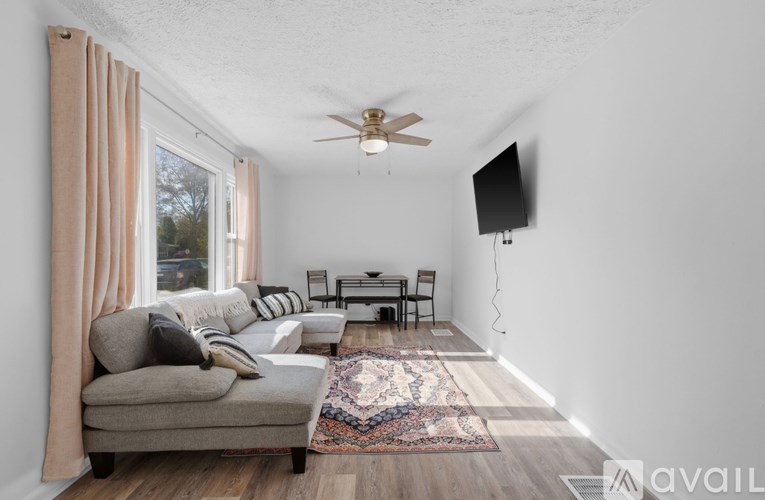 A living room with a couch, a rug, a table, and a television.