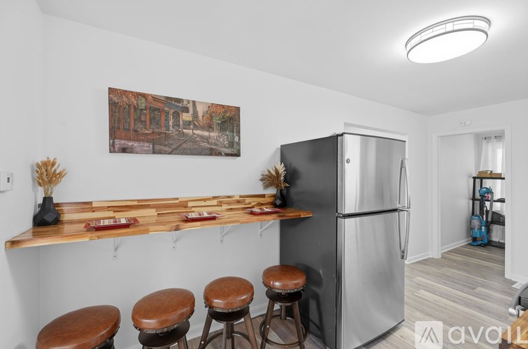 A kitchen with a refrigerator, bar stools, and a painting on the wall.