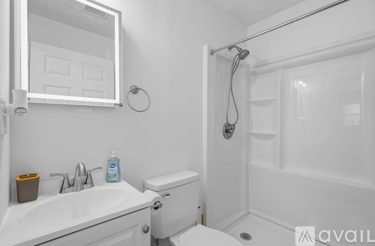 A white bathroom with a sink, toilet, and shower.