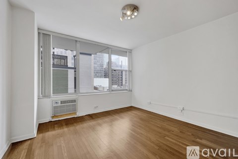 A room with wooden floors and a window overlooking a cityscape.
