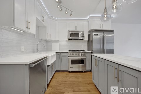 A modern kitchen with stainless steel appliances and wooden floors.