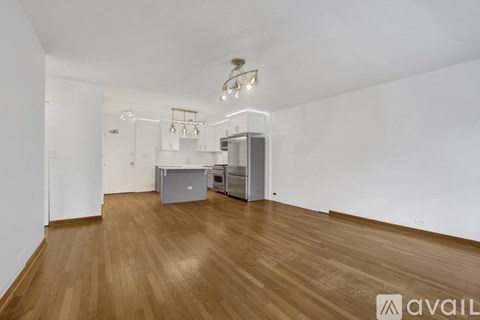 A room with wooden floors and a kitchenette in the corner.