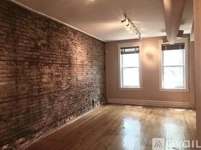 A room with a brick wall and wooden flooring.