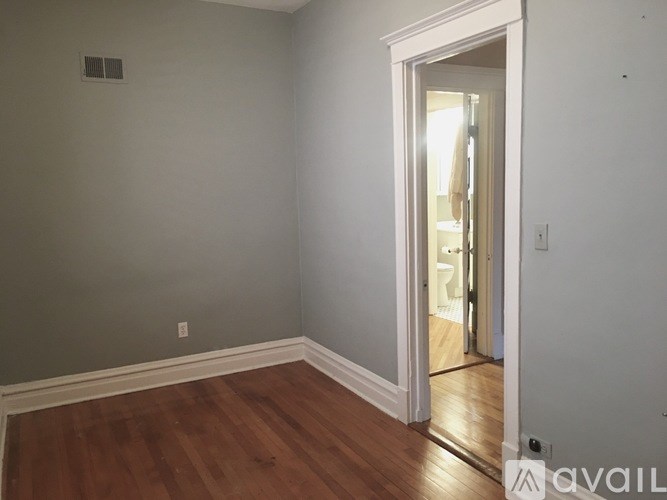 A room with a wooden floor and a white door leading to another room.