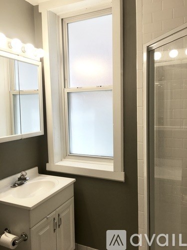 A bathroom with a sink, mirror, and window.