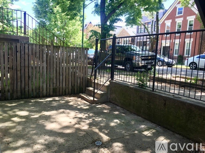 A black truck is parked behind a black metal fence.