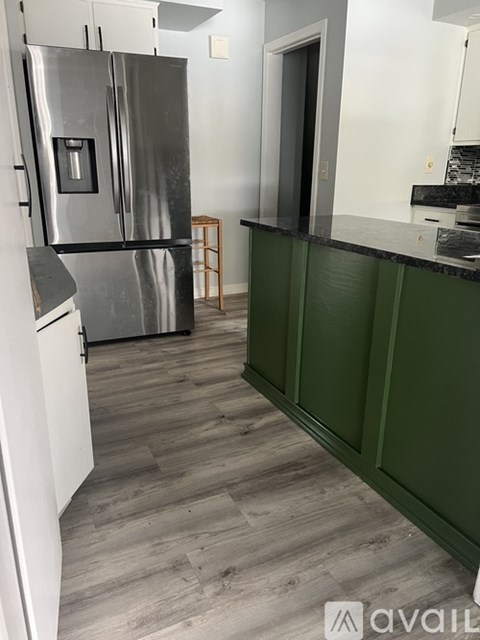 A kitchen with a stainless steel refrigerator and green cabinets.