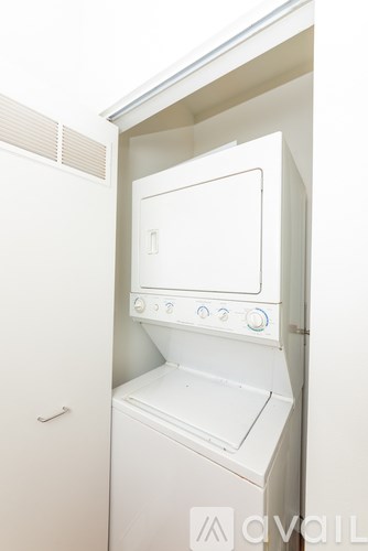 A white dryer is in a small, white-walled laundry room.
