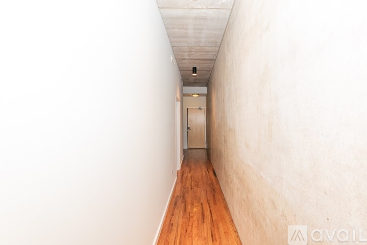 A long hallway with a wooden floor and a white wall on the left.