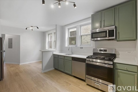 A kitchen with green cabinets and stainless steel appliances.