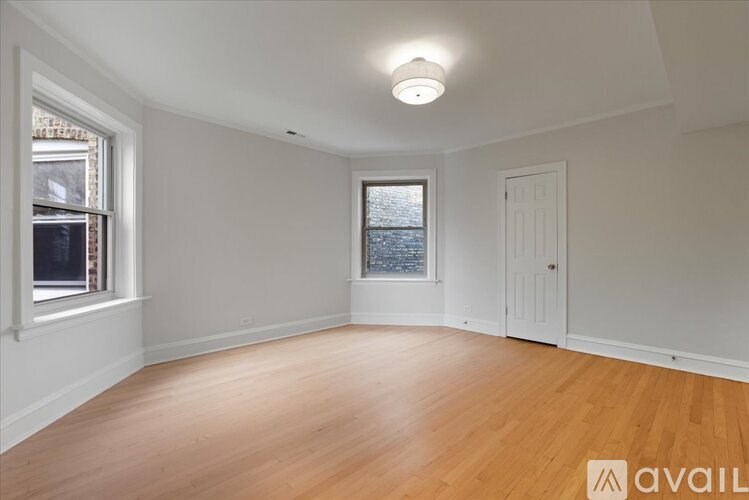 A room with wooden floors and two windows.