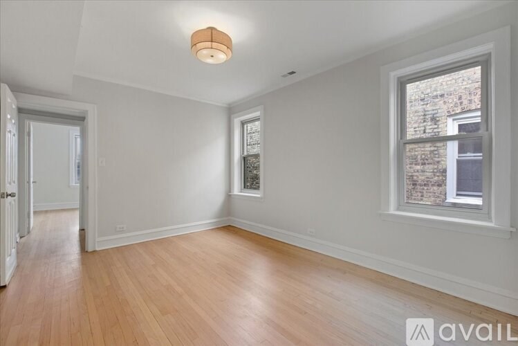 A room with wooden floors and a window showing a brick wall outside.