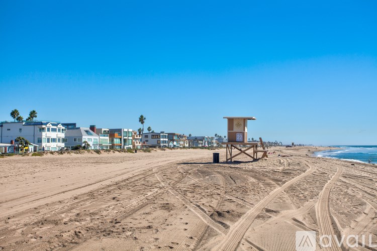 A beach with a lifeguard tower and tire tracks in the sand.