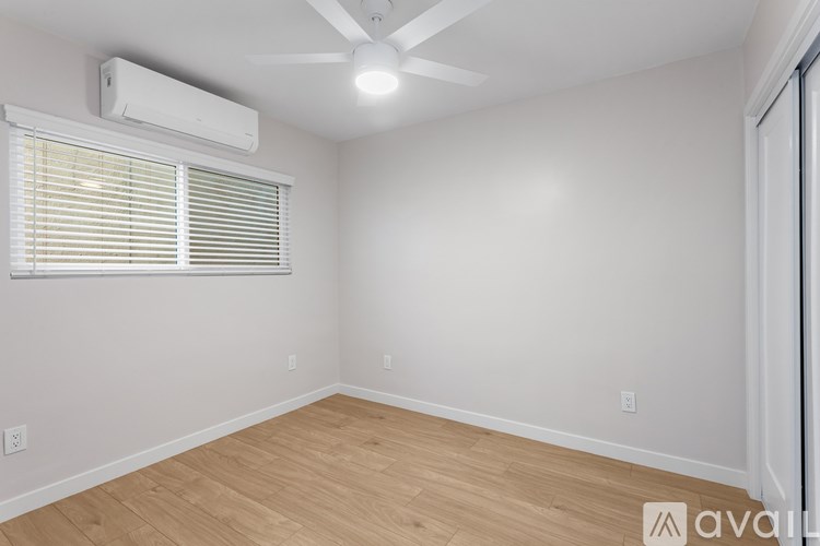 A room with a ceiling fan and a window with blinds.