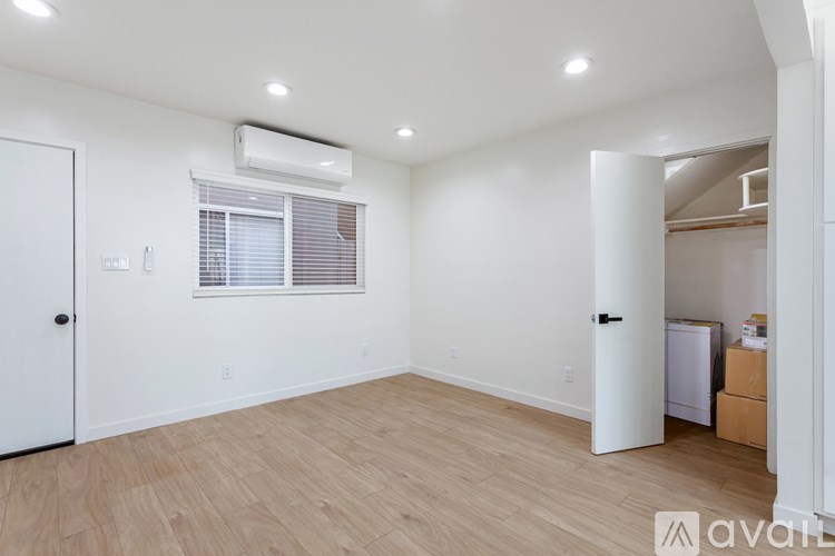 A room with wooden flooring and a window with blinds.