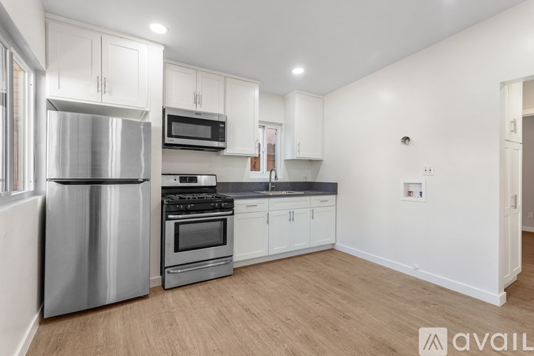 A modern kitchen with white cabinets and stainless steel appliances.
