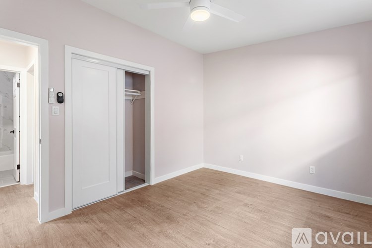 A room with a white door and a ceiling fan.