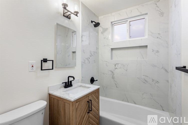 A bathroom with a marble wall and a wooden cabinet.