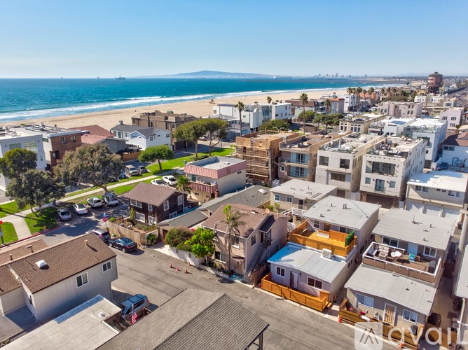A coastal residential area with houses and a beach in the distance.