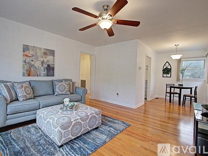 A living room with a grey couch, a coffee table, and a ceiling fan.