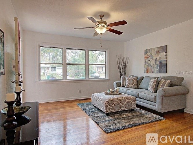 A living room with a grey couch, a rug, a coffee table and a ceiling fan.