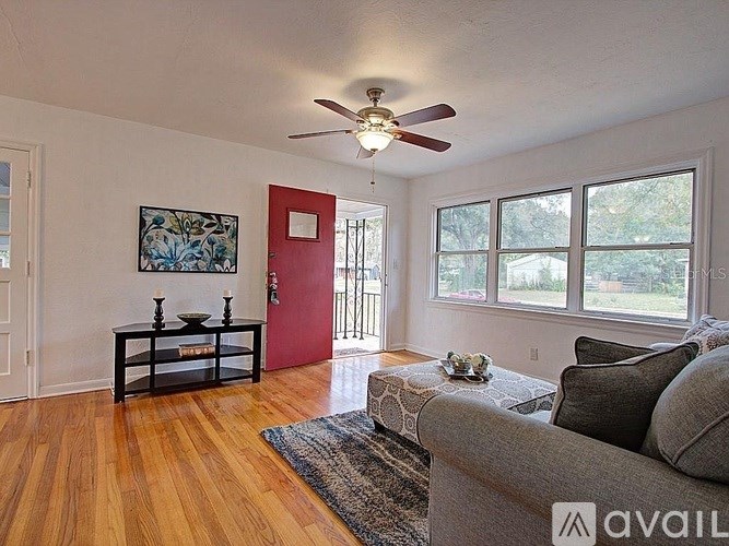 A living room with a grey couch and a ceiling fan.