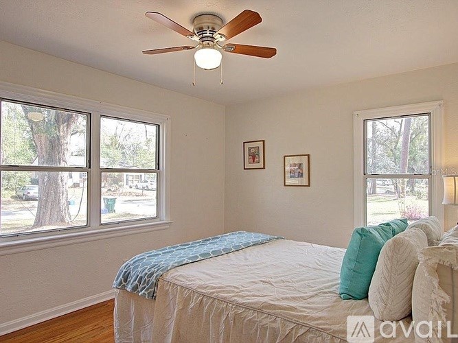 A bedroom with a bed, a ceiling fan, and two windows.