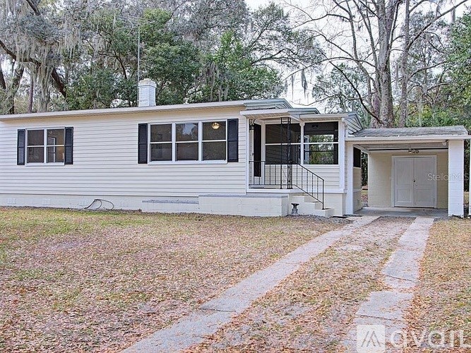 A white mobile home with a black railing on the porch.