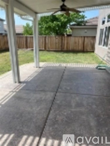 A patio with a ceiling fan and a concrete floor.
