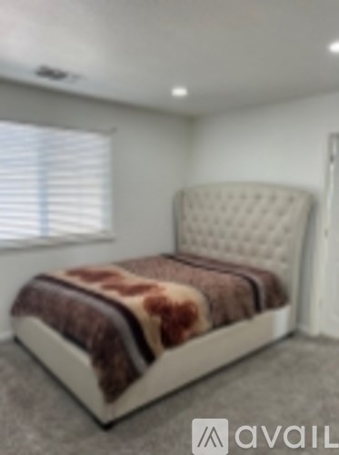 A bed with a brown and white comforter is in a room with a window.