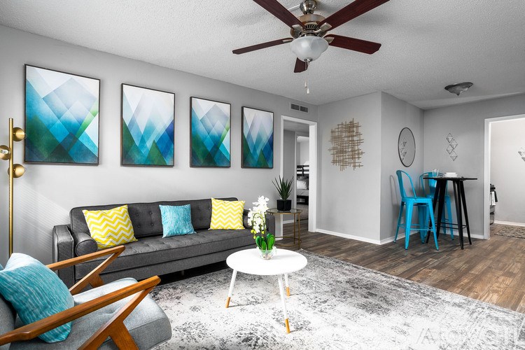 A living room with a grey couch, a white coffee table, and a ceiling fan.