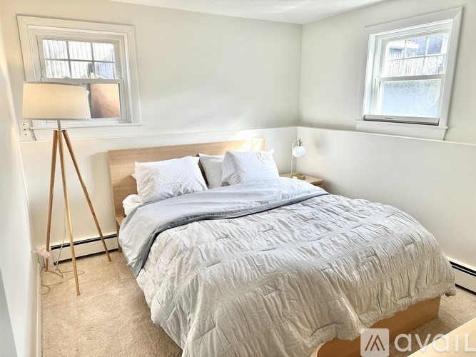 A bedroom with a bed, a lamp, and a window.