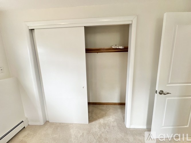A white door is open to reveal a small closet with a shelf.