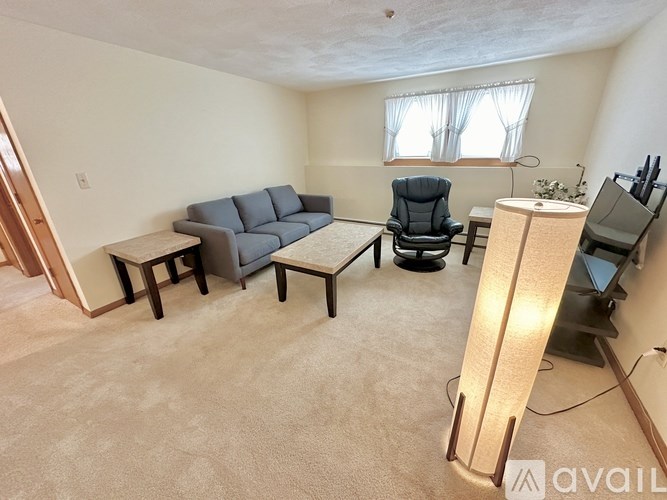 A living room with a grey couch, a black chair, a wooden coffee table, and a television.