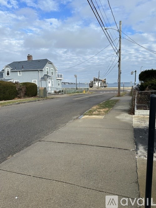 A street view with a house on the left and a pole on the right.